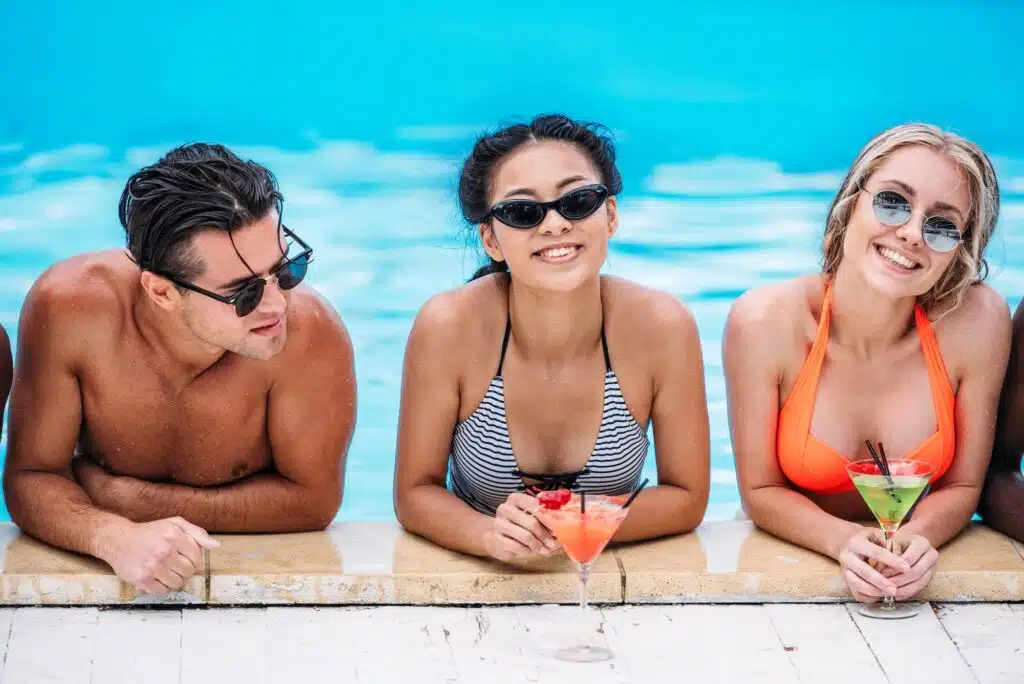 Gruppe junger glücklicher multiethnischer Menschen mit Cocktails im Swim Spa